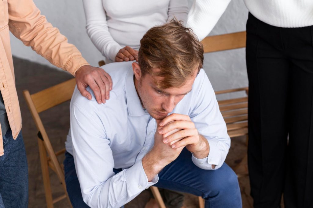 sad man sitting chair group therapy session min